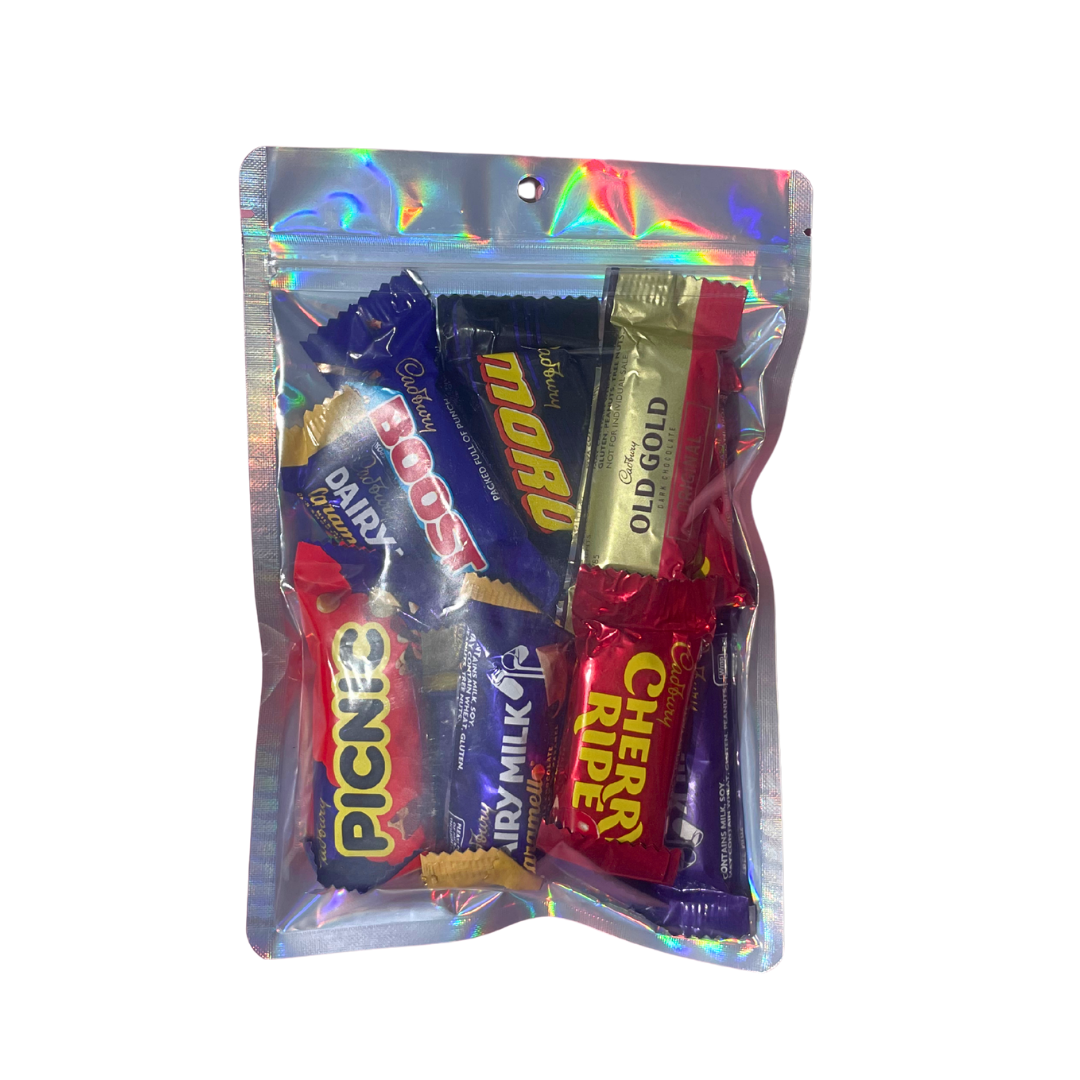 Packaged assorted candy bars including Cadbury, Nestle, and more in a reflective plastic bag on a white background.