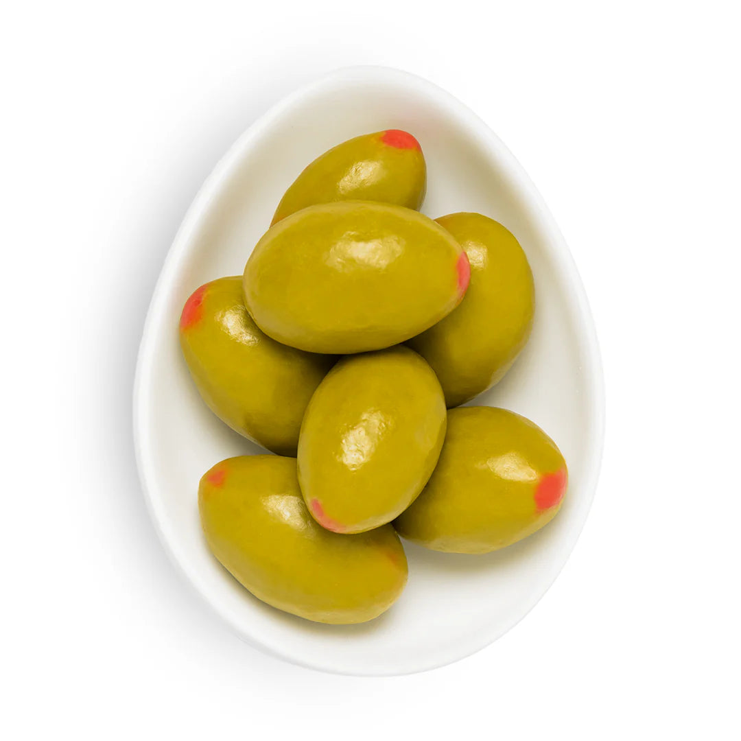 Green olives shaped chocolate covered almonds with red tips on a white plate