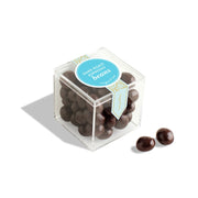 Clear cube container with dark chocolate beans and a blue label on a white background