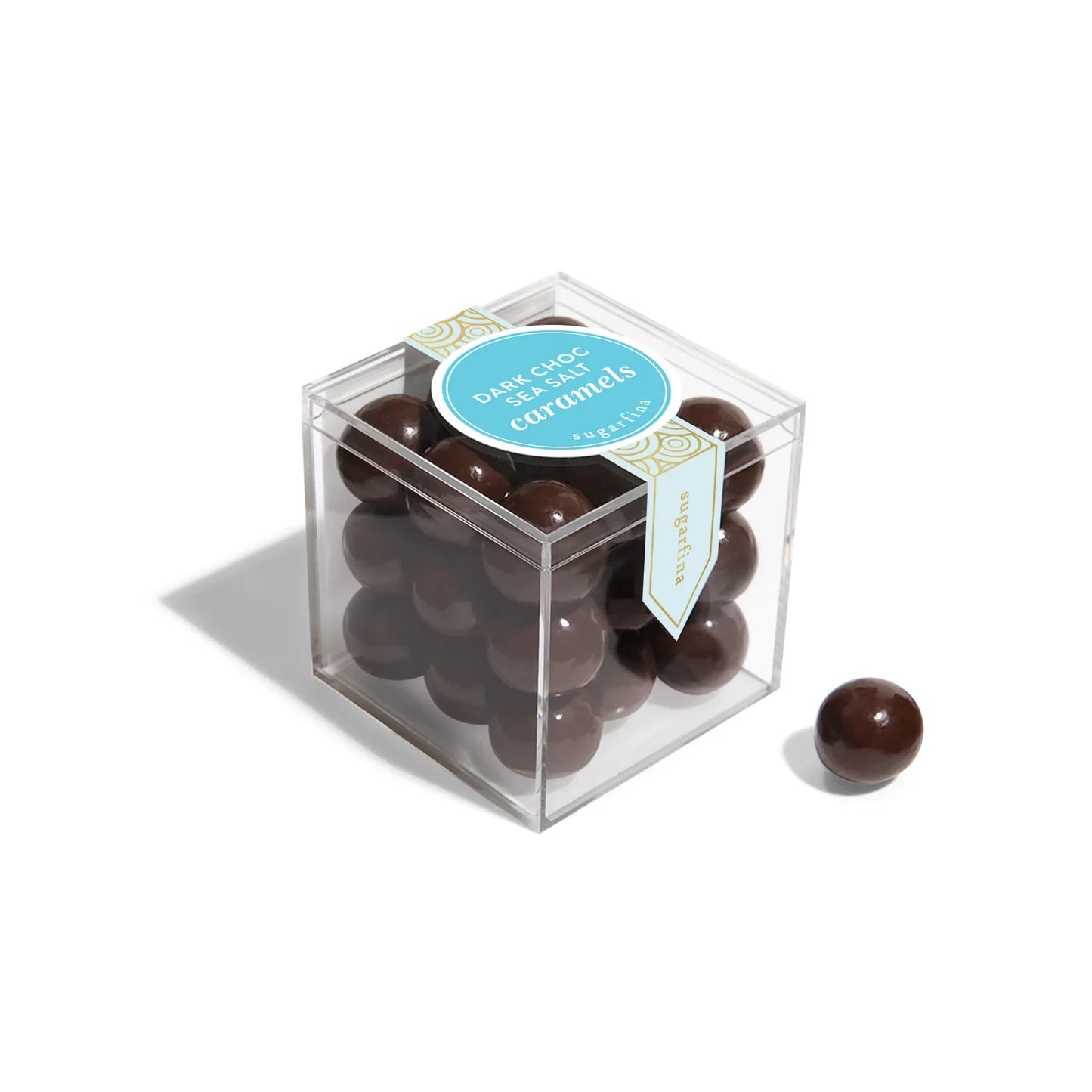Clear cube box filled with chocolate-covered caramel on a white background