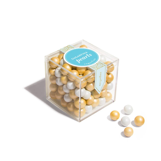 Clear cube container filled with yellow and white pearl shaped chocolate on a white background